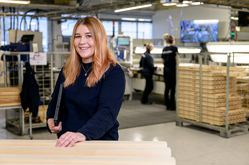 Kvinna står i en produktionslokal med ett leende