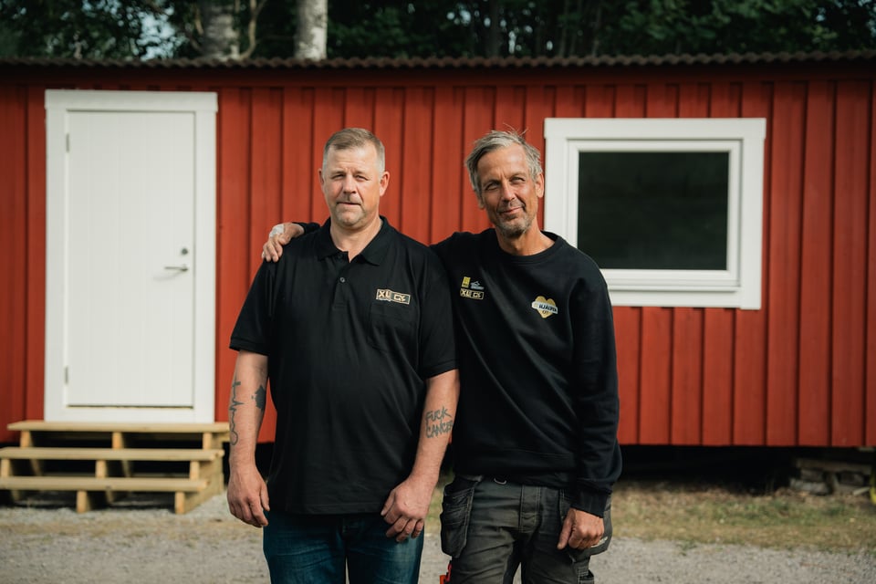 Två personer framför ett rött hus