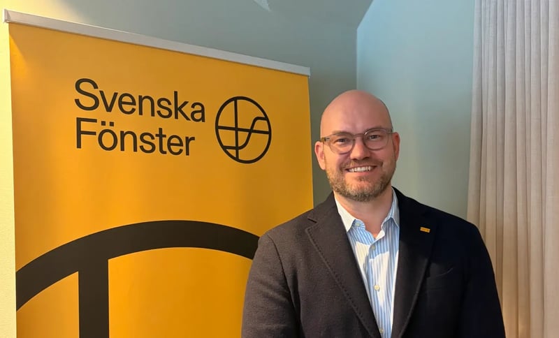 Michael Juhl, ler och står framför en Svenska Fönster skylt